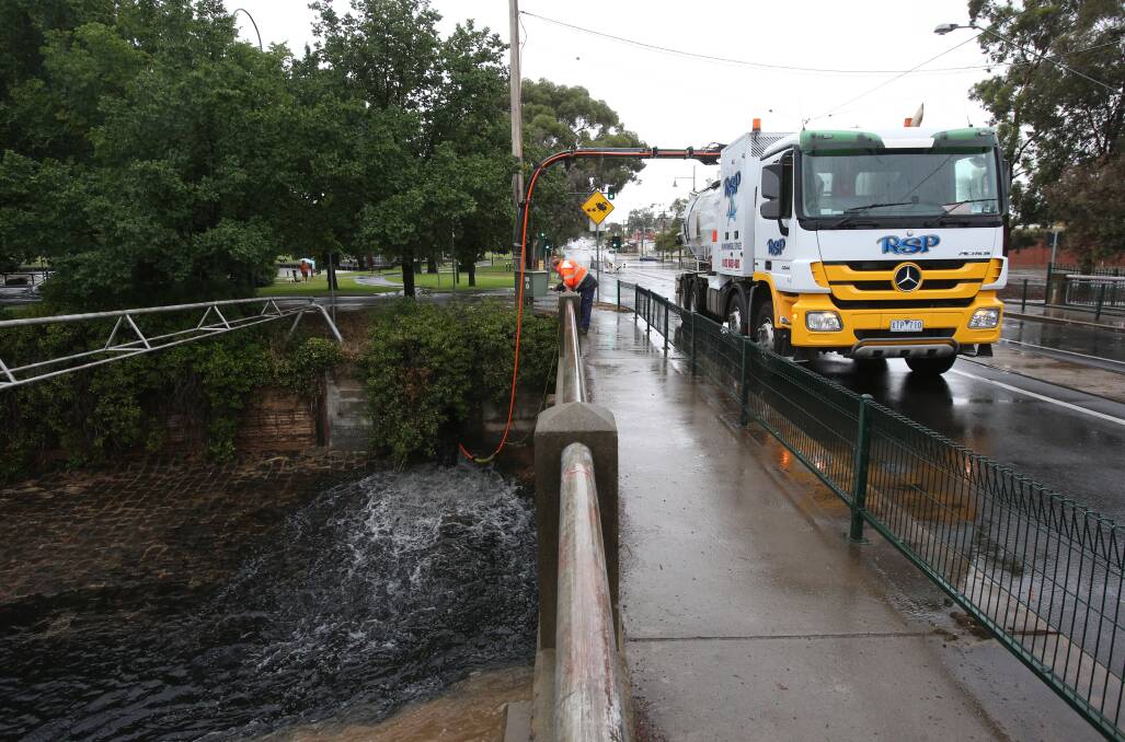 Workers try to unblock a drain in Nolan Street near the Bendigo Tennis Complex. Picture: PETER WEAVING