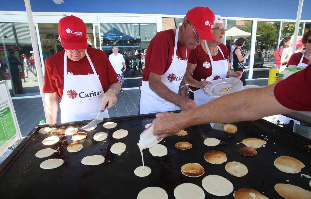 Patrick Kempton with Roger and Tricia Newman work the pancakes for Caritas.
Picture: PETER WEAVING
