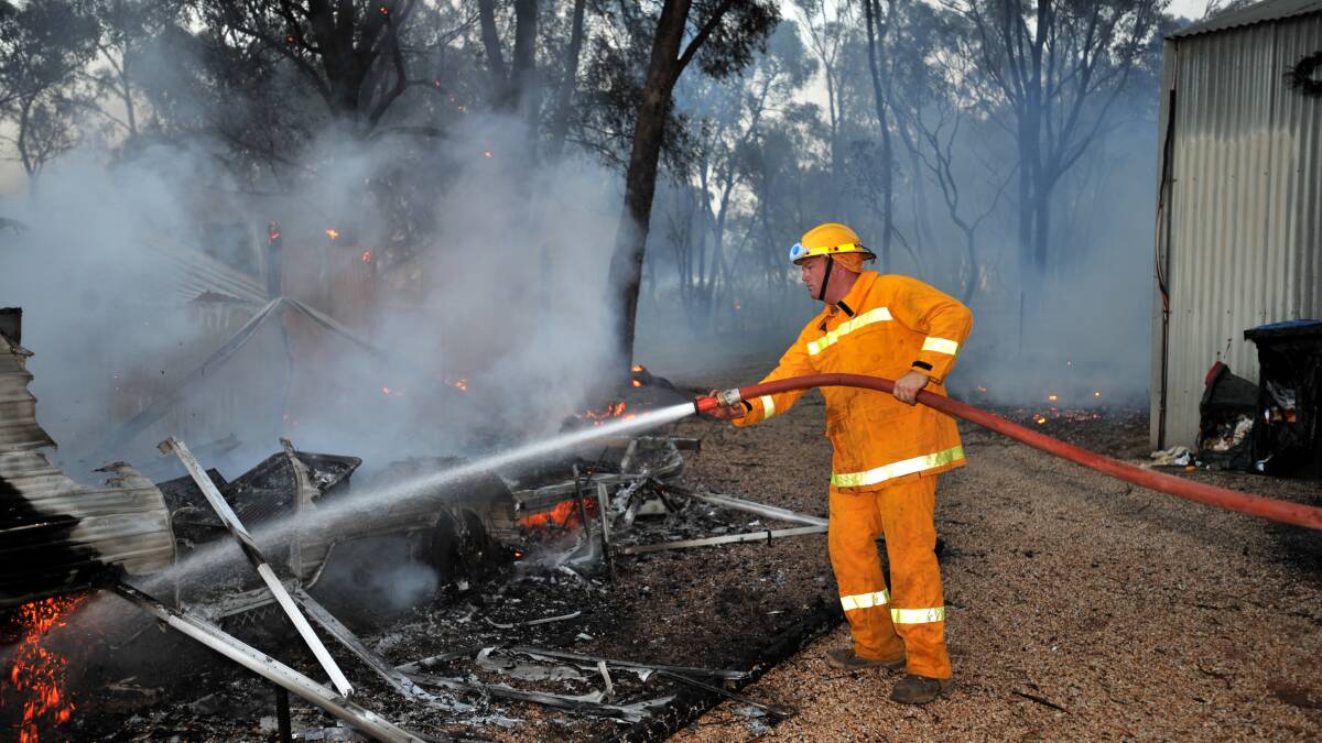 FEBRUARY 7, 2009: A Raywood firefighter douses a caravan burnt in the fire in Maiden Gully Road. Picture: Peter Hyett