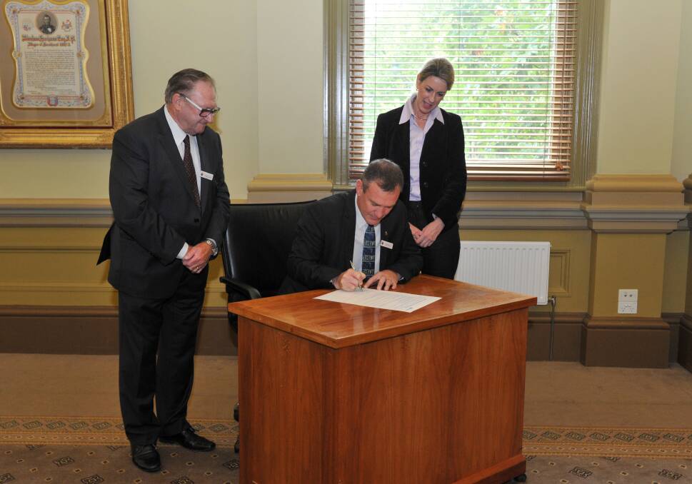 DECLARATION: Greater Bendigo chief executive Craig Niemann signs the Greater Bendigo Wellbeing Charter in the presence of Cr Barry Lyons and the Parliamentary Secretary for Health Georgie Crozier. Picture: JODIE DONNELLAN 
