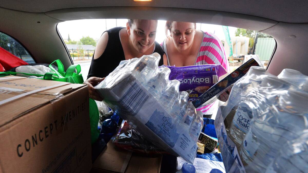 HELPING HAND: Twin sisters Emily and Tina Batterham load up their car to make a delivery to firefighters. Picture: BRENDAN McCARTHY