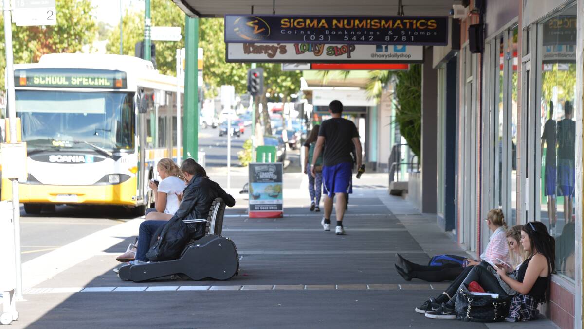 Bus passengers using both the bench and the footpath for sitting in Mitchell Street this week. Picture: BRENDAN McCARTHY
