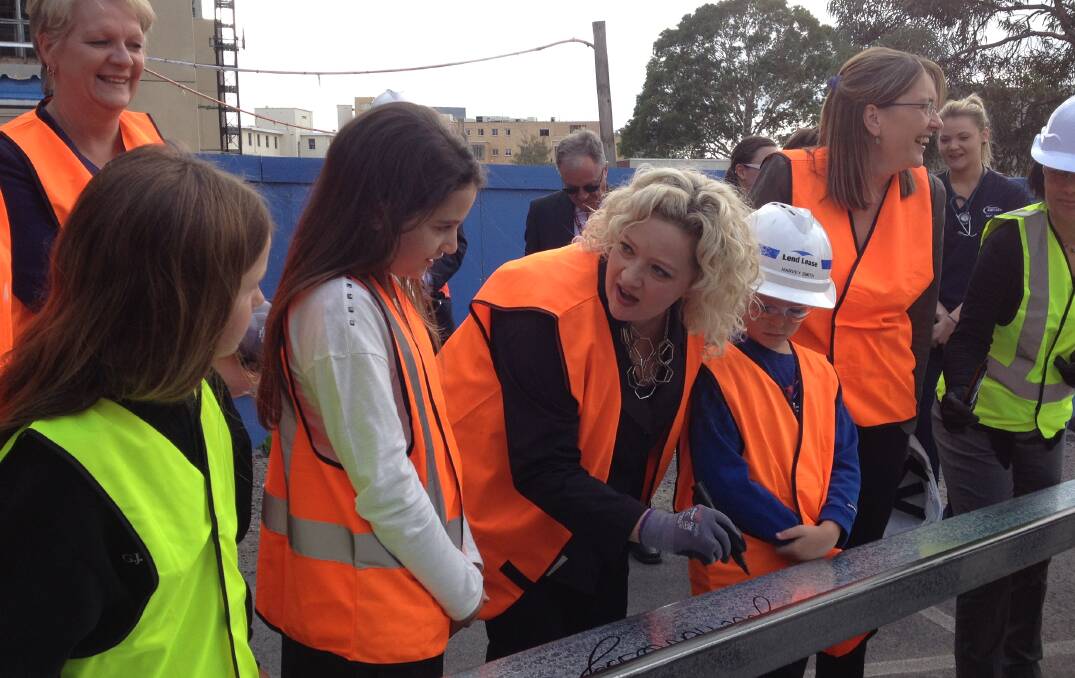 Health Minister Jill Hennessy signs the beam with the children who named the cranes at the hospital site.