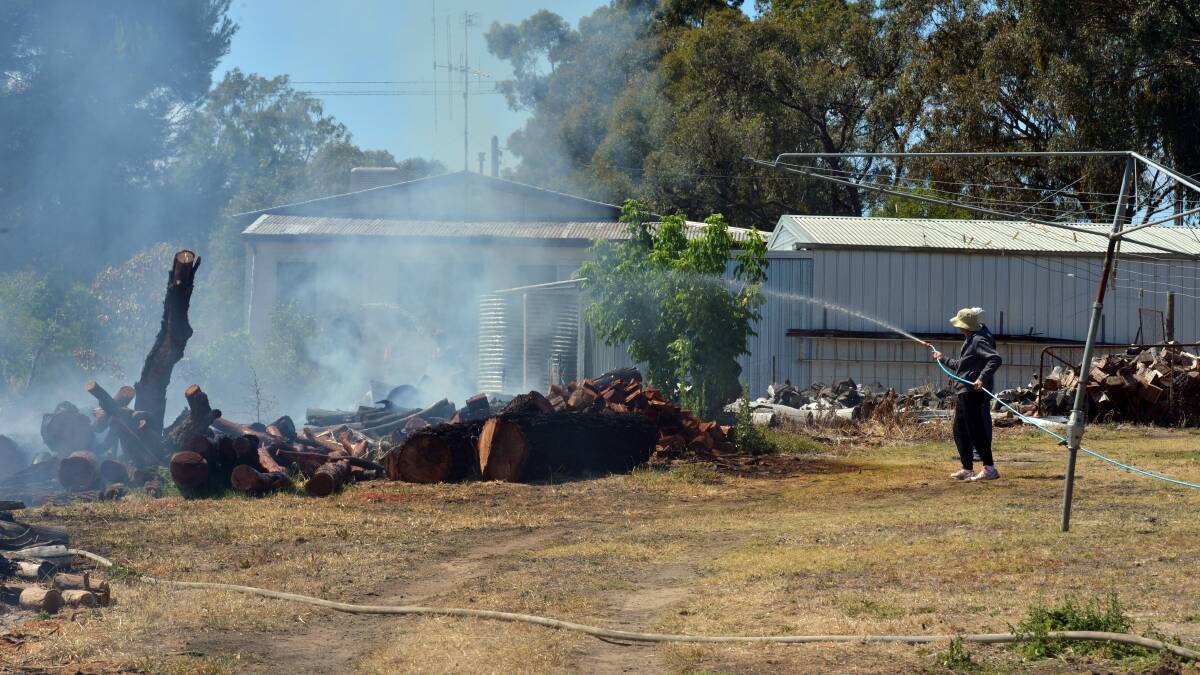 OPTIMISTIC: A resident uses a garden hose on a fire in Phillis Street, Kangaroo Flat. Picture: BRENDAN McCARTHY