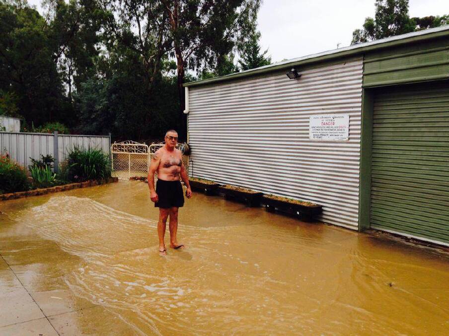 Tony Pangallo watches water flow through the yard of his Holdsworth Road home from a nearby creek. Picture: JIM ALDERSEY