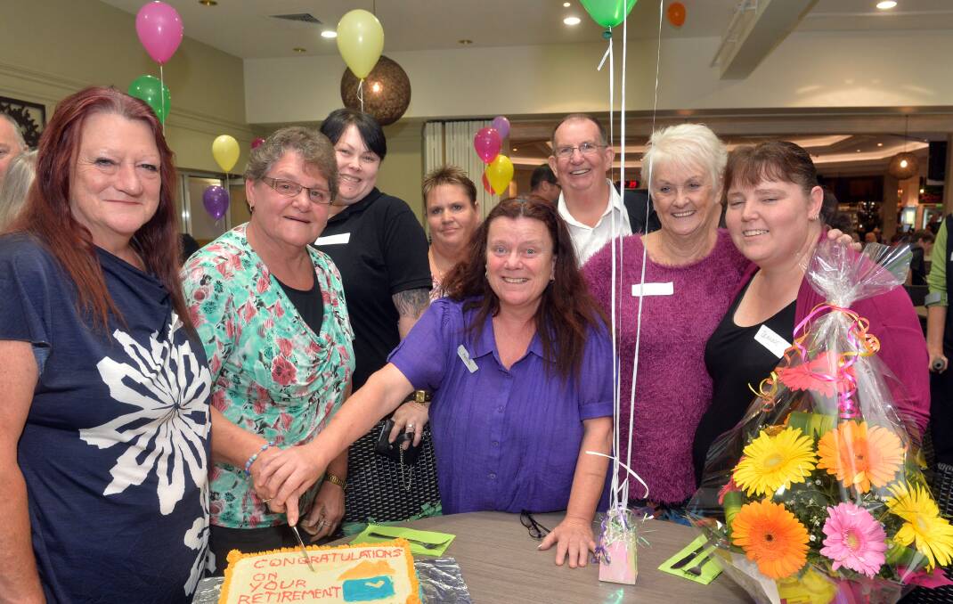 CELEBRATE: Carolyn cutting the cake with well-wishers
