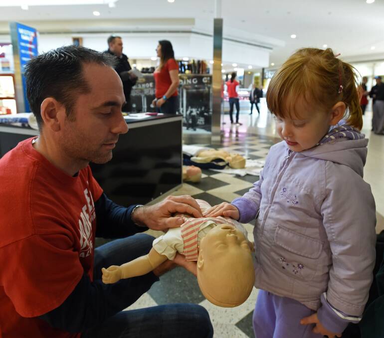 TEACHING: Paramedic Greg Colt shows Emily Campbell, 4, some CPR tips. Picture: JODIE DONNELLAN