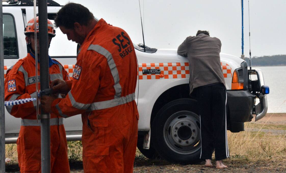SCENE: A man hunches over an SES truck as emergency crews seek a missing man