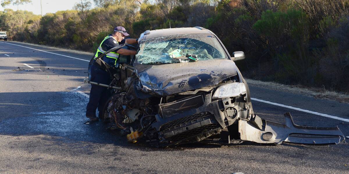 CRASH: A police officer inspects a car which hit a truck in Inglewood. Picture: JIM ALDERSEY