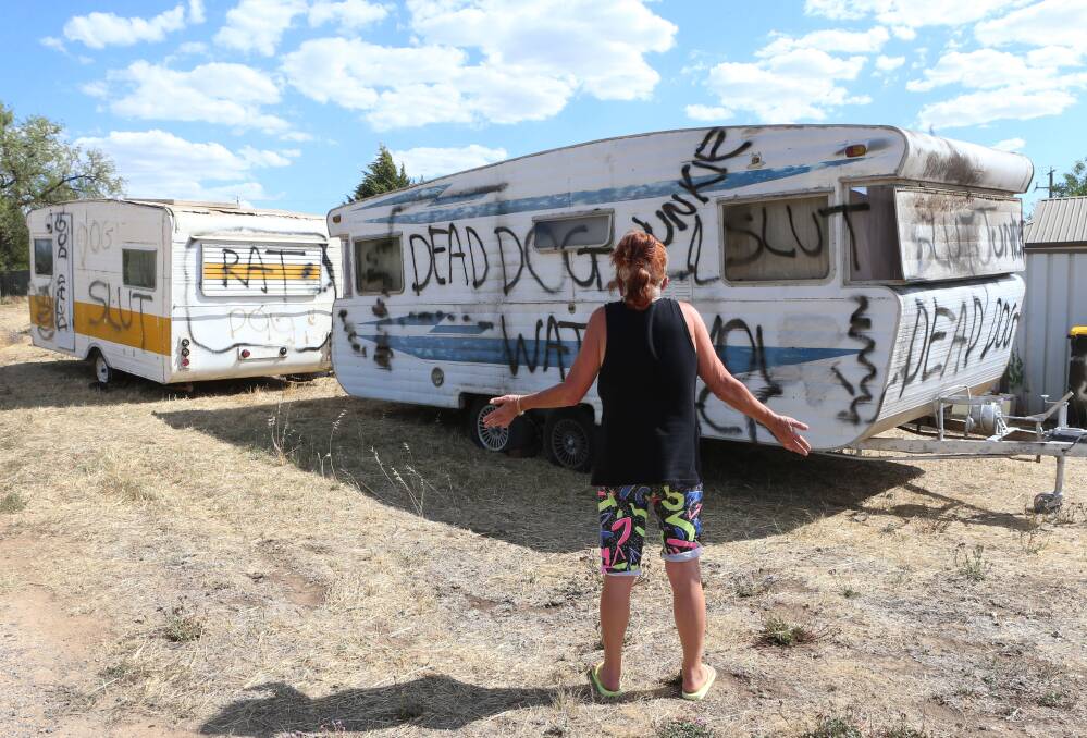 FEARS: A woman inspects two caravans littered with threats and profanities. Picture: PETER WEAVING