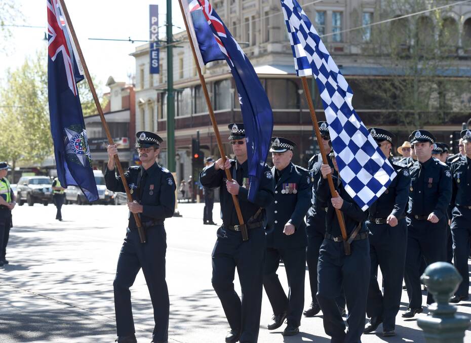 FLAG BEARER: Sergeant Mark Holloway leads a group of police members at the procession for the National Police Remembrance Day service in central Bendigo on Monday. Picture: JODIE DONNELLAN
