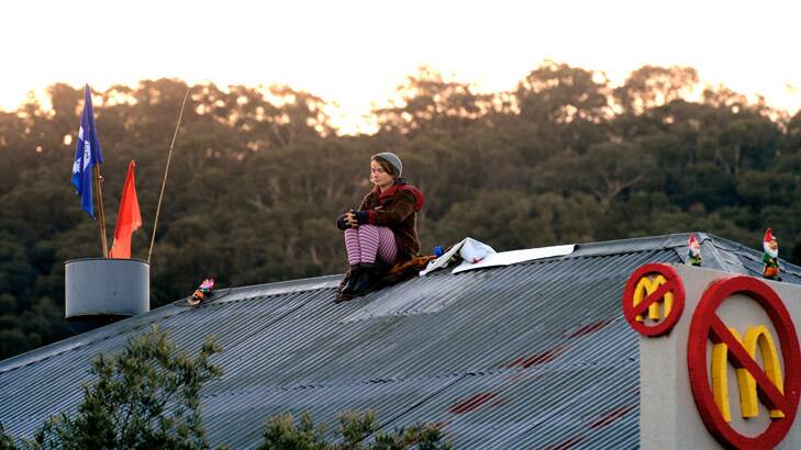 A protester sits on the roof of the proposed McDonald's in Tecoma. Photo: Penny Stephens