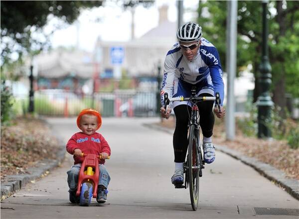 MASTER AND THE APPRENTICE: David Pell warms up for tonight's criterium through Rosalind Park through Rosalind Park with two-year-old Orin McKay. Picture: BILL CONROY