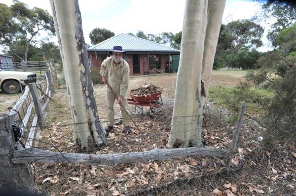 Proactive: Emu Creek Fireguard Group co-ordinator John Wells sets an example as he keeps his property bushfire ready this season by removing the flammable dead leaves near his house.  Picture: Peter Weaving