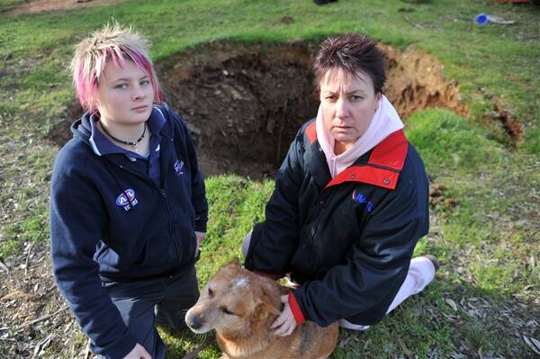 Woodvale residents Julie Perceval and her daughter Michaela next to a deep mine shaft that has opened up on their property after recent heavy rain.                                             Picture: BILL CONROY