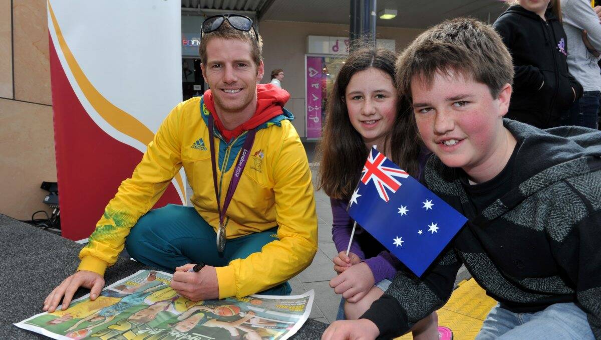 SILVER STAR: Glenn O’Shea signs a Bendigo Advertiser Olympic poster for Sam and Ruby Kane in the Hargreaves Mall. Picture: JULIE HOUGH