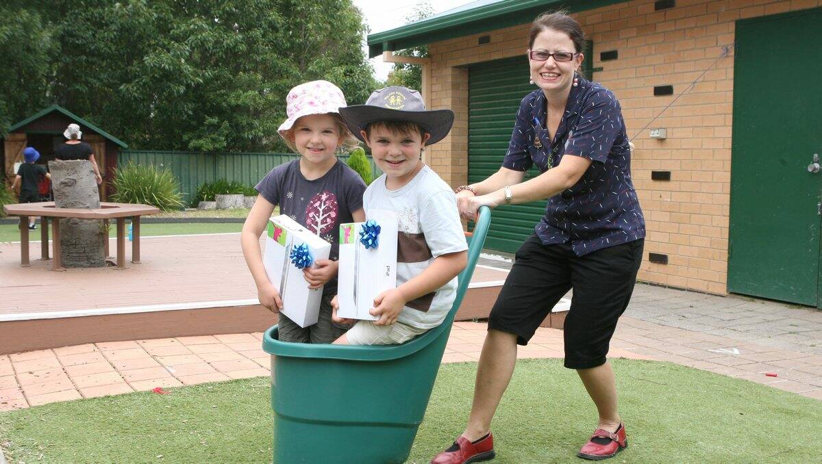 Wheelbarrow of coins: Five-year-olds Abbigail Grose and Charlie Harrison are pushed by early childhood educator Danielle Walker.  Picture: PETER WEAVING