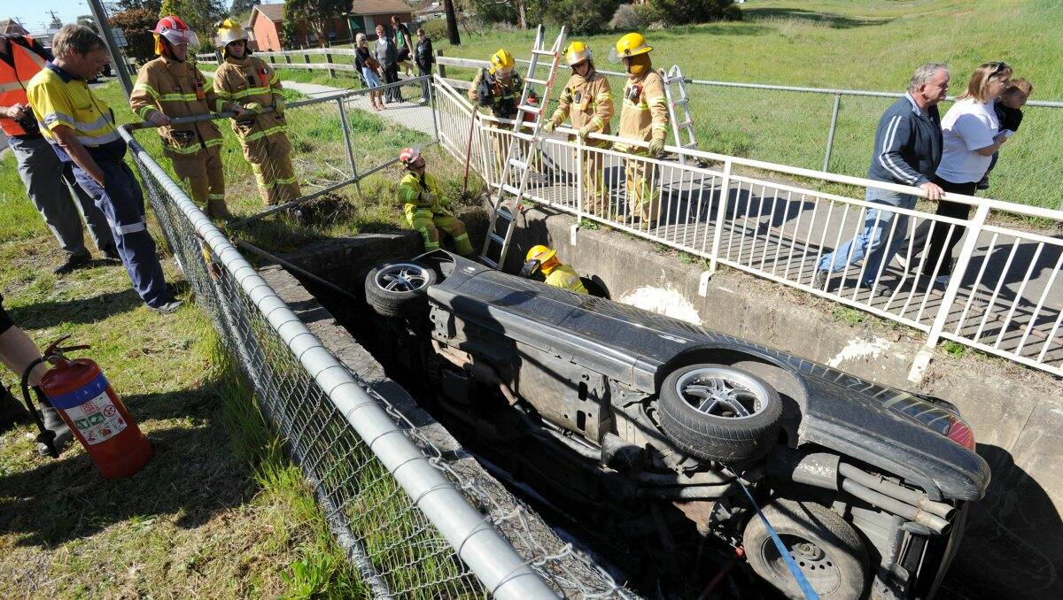 Draining day: Fire crews ponder the best way to remove the wreckage. Picture: Peter Weaving