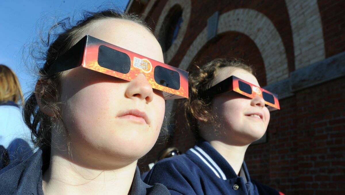 CAPTIVATED: Seven-year-old Arwen and 10-year-old Eve Fetherstonhough were among those who watched yesterday’s partial solar eclipse. Picture: PETER WEAVING