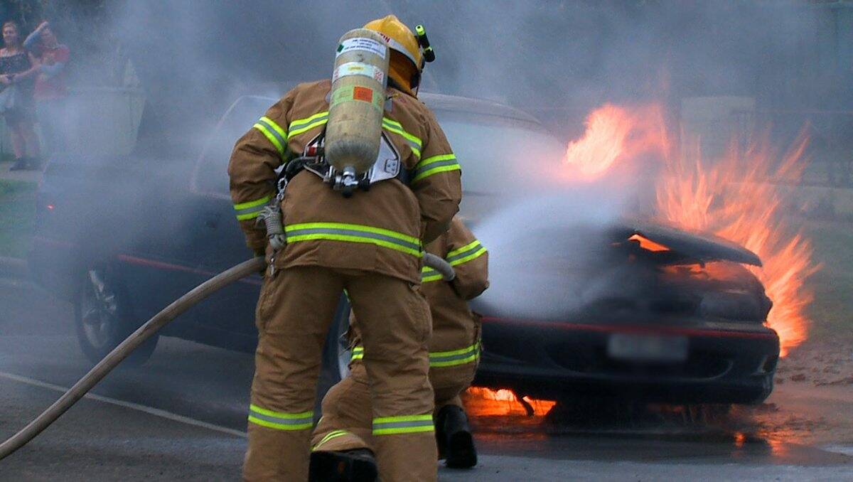 Response: CFA members douse the burning car in High Street yesterday. Picture: Apex Imagery