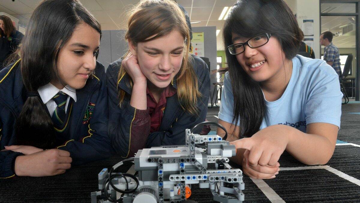Amy Mallia and Caitlyn McHutchison work on a robot vehicle with Robogals’ Shirley Tian. Picture: Brendan McCarthy