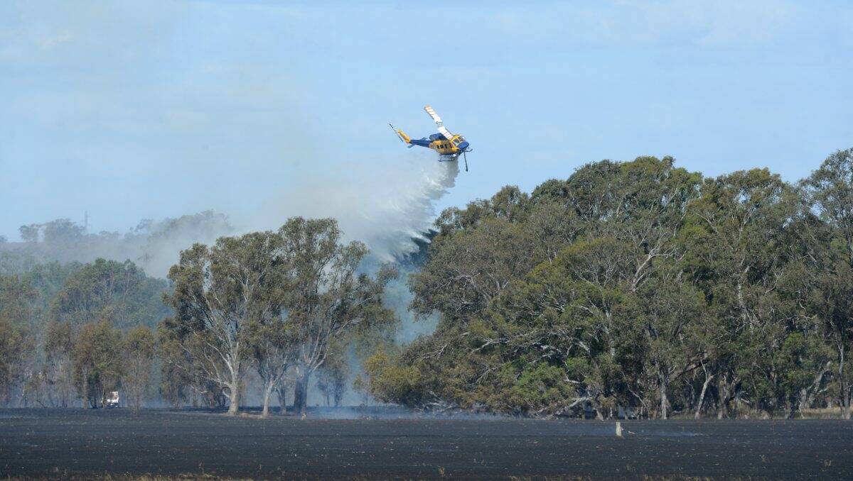 Dry: A fire-bombing helicopter helps bring the Toolleen blaze under control yesterday. Picture: Jim Aldersey