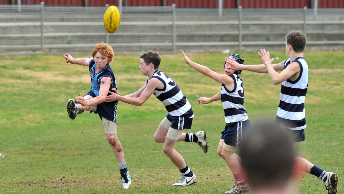 BEST AFIELD: Eaglehawk's Koby Hommelhoff kicks as Strathfieledsaye's Tom Fitzgerald, Cal McCarty and Jordy Garland charge in during the under-14 match at Canterbury Park. Picture: PETER WEAVING