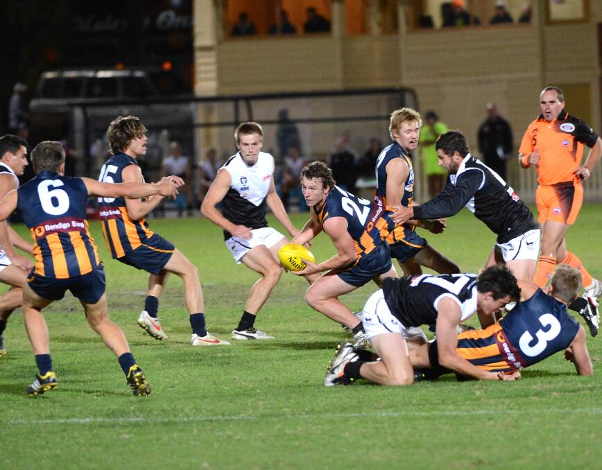 HEAT IS ON: Bendigo Gold’s Alex Pollock looks to dish off a handball against North Ballarat.   Picture: JODIE DONNELLAN 