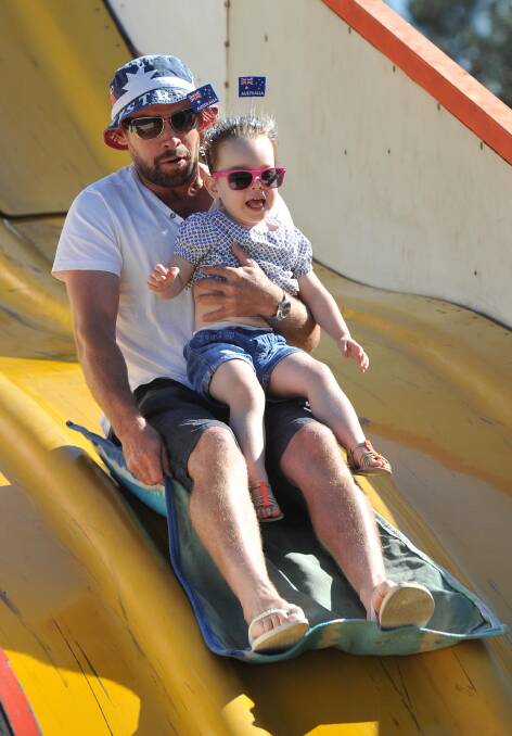 Alastair Robb with daughter Zoe, 2, have a ride on the giant slide at the Wagga Australia Day breakfast and citizenship ceremony. Picture: Michael Frogley