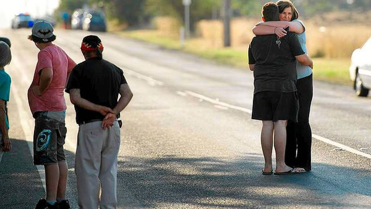A man and woman embrace as they meet on Craigieburn Road while waiting to get back to their homes, which had been blocked off by the grassfire. Photo: Jason South
