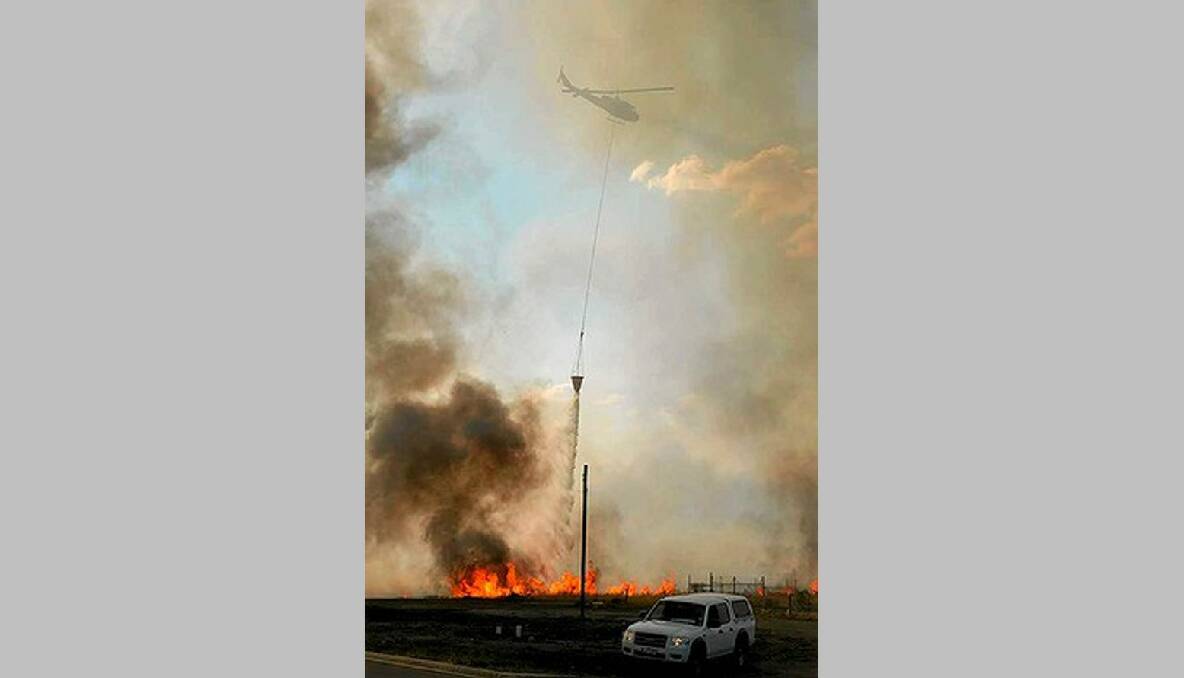 A helicopter water bombs the grassfire. Photo: Jason South