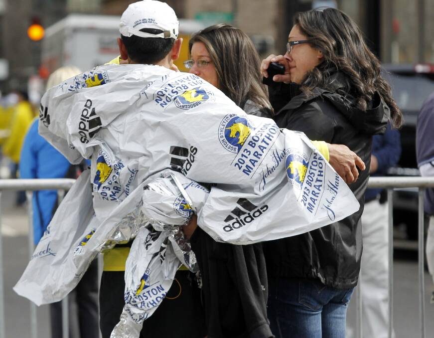 People comfort each other while emergency services attend the scene of the Boston blasts. Photo: Reuters