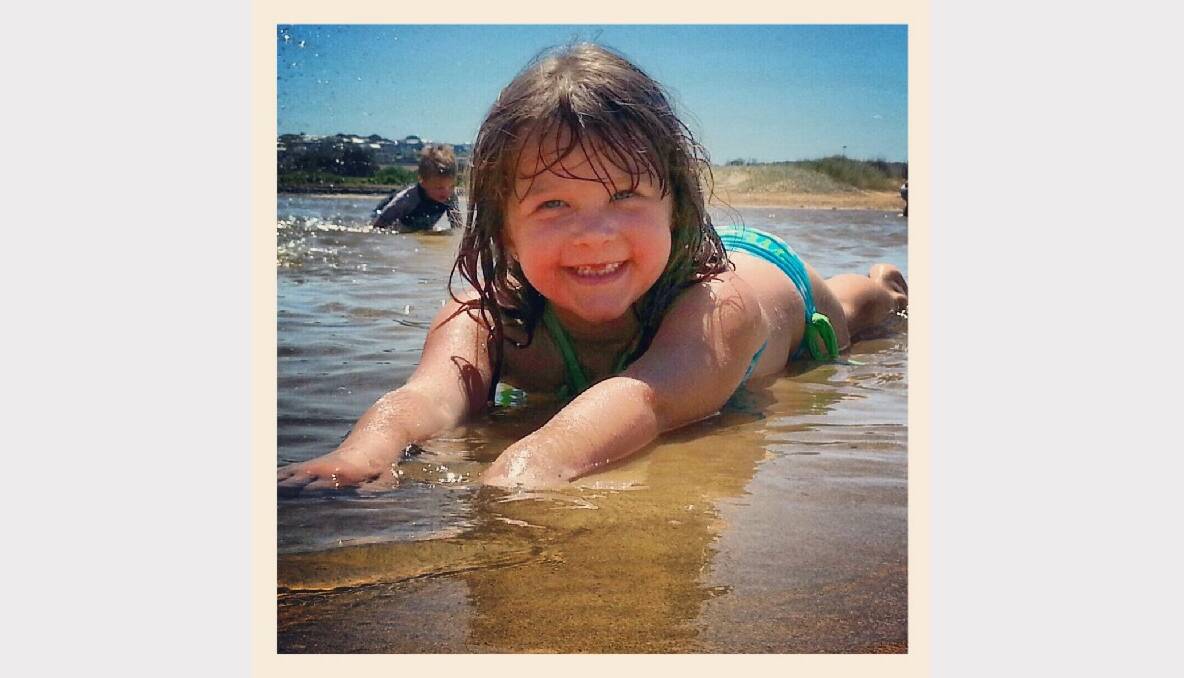 Tayah Phillips lies in the warm waters of the beach at Torquay. Picture: Jenna Phillips