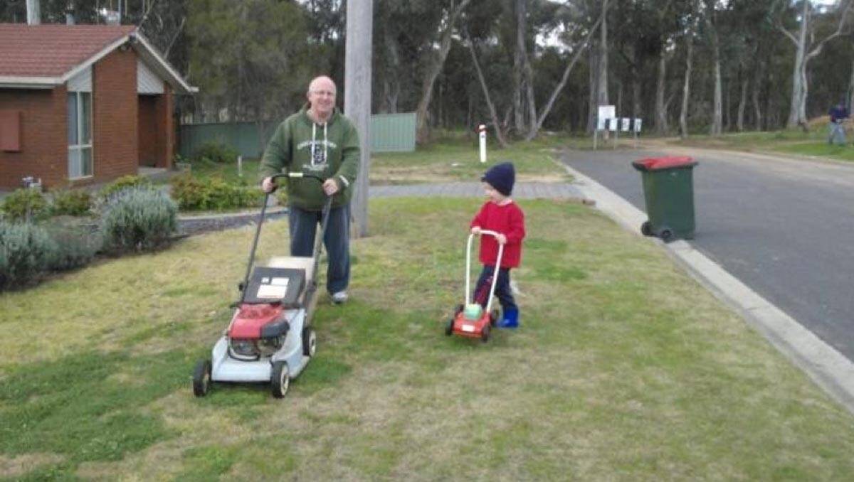 Max Claridge helping his Grandpa mow the lawn. Picture: Bruce Claridge