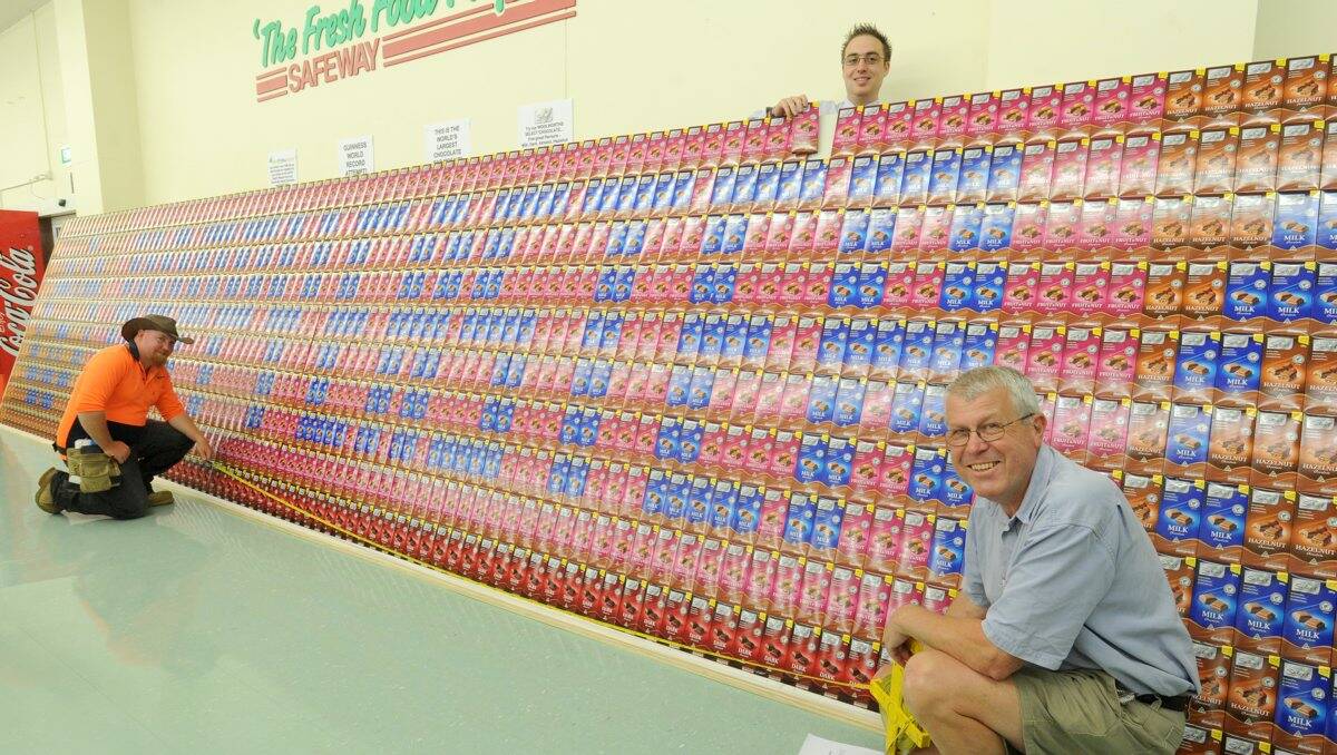 WORLD FIRST: Store manager Ben Dillon stacks the final block of chocolate while local surveying consultants Tomkinson Group’s Josh Ivins (left) and Kevin Thield measure the record attempt. Picture: JODIE DONNELLAN