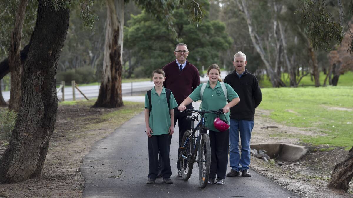 COMMUNITY PATH: St Francis of the Fields Primary School principal Tim Moloney, Strathfieldsaye and Districts Community Enterprise (SDCE) chairman Dennis Johanson and students Tate Kanzamar and Aysha O'Kane on the footpath the community rallied to seal. Picture: NONI HYETT