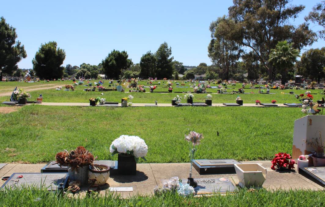 Lawn graves, some adorned with broken items, at Bendigo Cemetery.