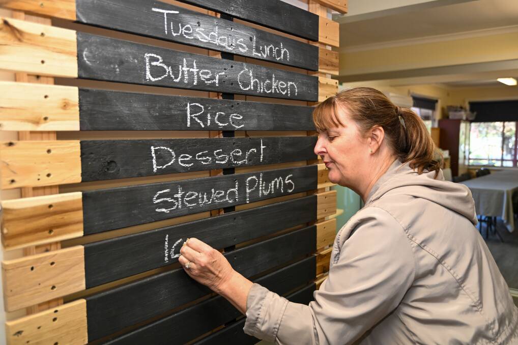 Tracey Moss writes up the menu for a community lunch at the centre. Picture by Enzo Tomasiello