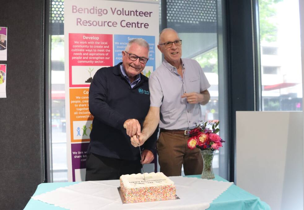 Long-time Bendigo volunteers David Wright and Paul Kirkpatrick cut the cake to celebrate International Volunteer Day. Picture by Lucy Williams 