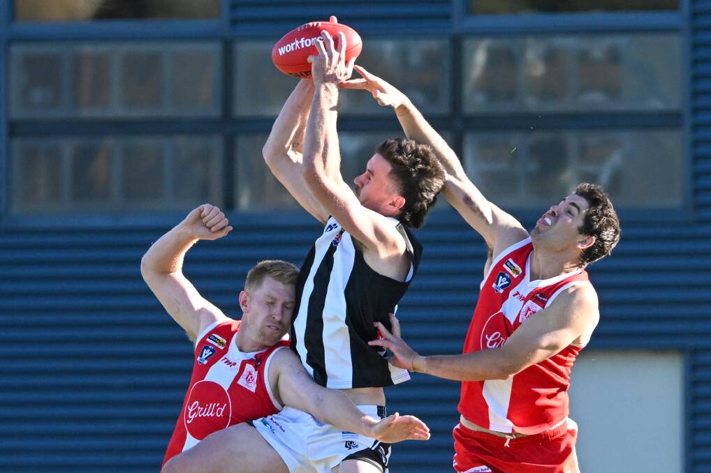Castlemaine coach Michael Hartley leaps for a mark with Bloods defender and co-coach Isaiah Miller attempting to spoil. Picture by Darren Howe