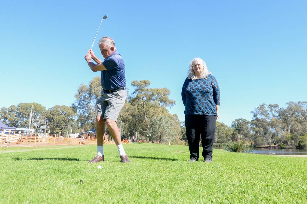 Rotary Club of Kangaroo Flat's Ian Doak hits a wedge shot towards the pin at Rotary Gateway Park while president Kaylyn Journeaux watches on, ahead of the Easter hole in one tournament at the weekend. Picture: DARREN HOWE