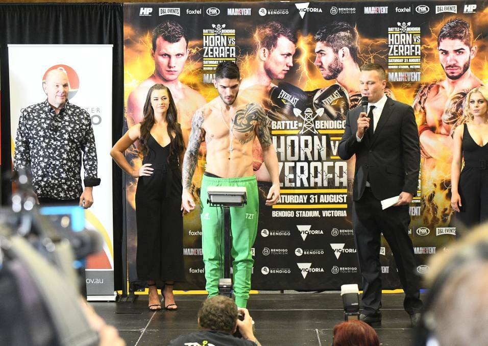 Michael Zerafa on the scales ahead of the Battle of Bendigo event, flanked by two "ring card girls". Picture: NONI HYETT
