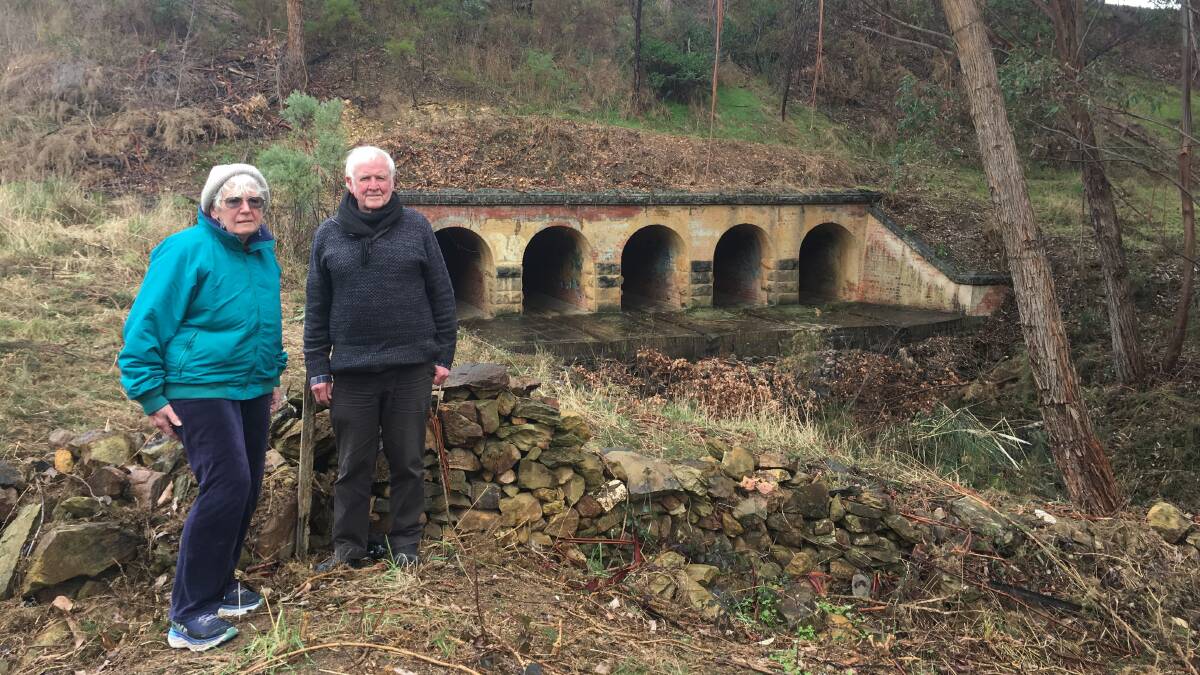 Pat Healy and John Ellis in front of the historic drainage system in Chewton, which was unearthed again following weed removal. Picture: ADAM HOLMES