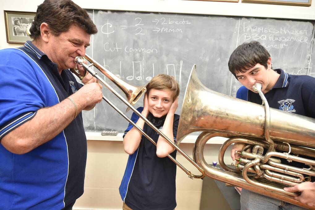 Lex Gray and Nick O'Connor prepare to give Henry Livingstone a blast at Marist Brass Band practice. Picture: DARREN HOWE