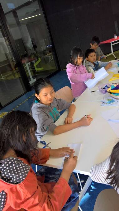 Children from Bendigo's Karen community work on illustrations for their children's book, which features images and explanations of traditional cultural practices.
