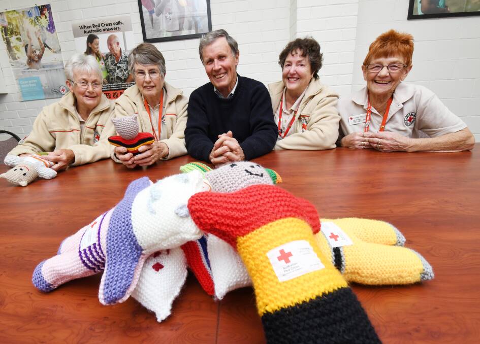 Red Cross Bendigo divisional operations officer Greg Ralton, centre, with emergency services volunteers Heather Sargeant, Gillian Wells, Carole Blake and Jill Moorhead. Knitted trauma teddies are in the foreground. Picture: DARREN HOWE