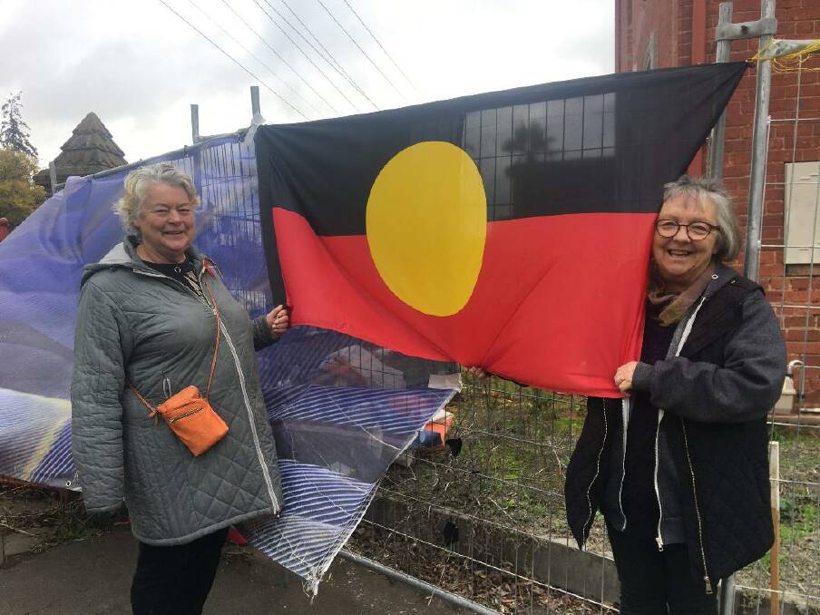 Janet Bromley and Gabby Gamble with the Aboriginal flag, which was returned to the fence outside the art fair. Picture: SUPPLIED