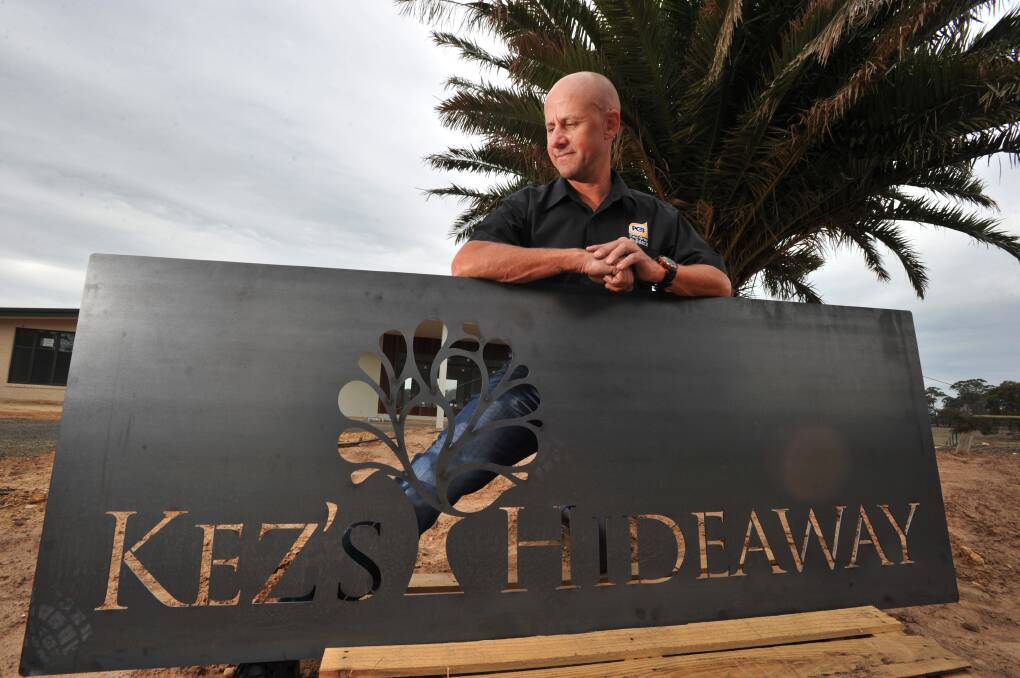 SIGN OF SUCCESS: Paul Gray with one of the two signs for Kez's Hideaway, back when the project was still under construction. He said the tree was symbolic of recovery. "You lose your leaves and they grow back." Picture: NONI HYETT