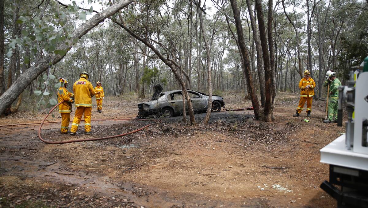 Firefighters tackle a burnt-out car at Mandurang South. Picture: EMMA D'AGOSTINO