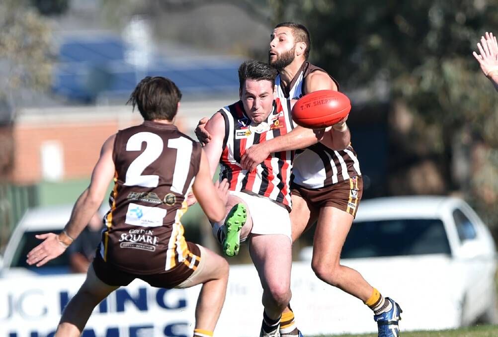 CONTESTED BALL: Heathcote's Jake Condon gets a kick away under pressure from Huntly's Ryan Semmel on Saturday. Semmel was best on ground. Picture: GLENN DANIELS